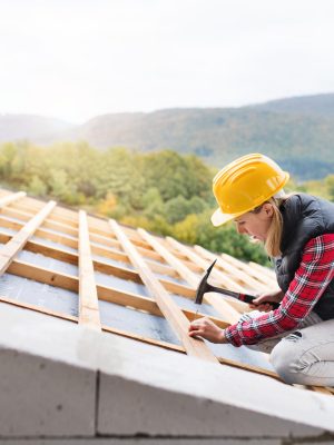 Young woman worker on the construction site. roofing services